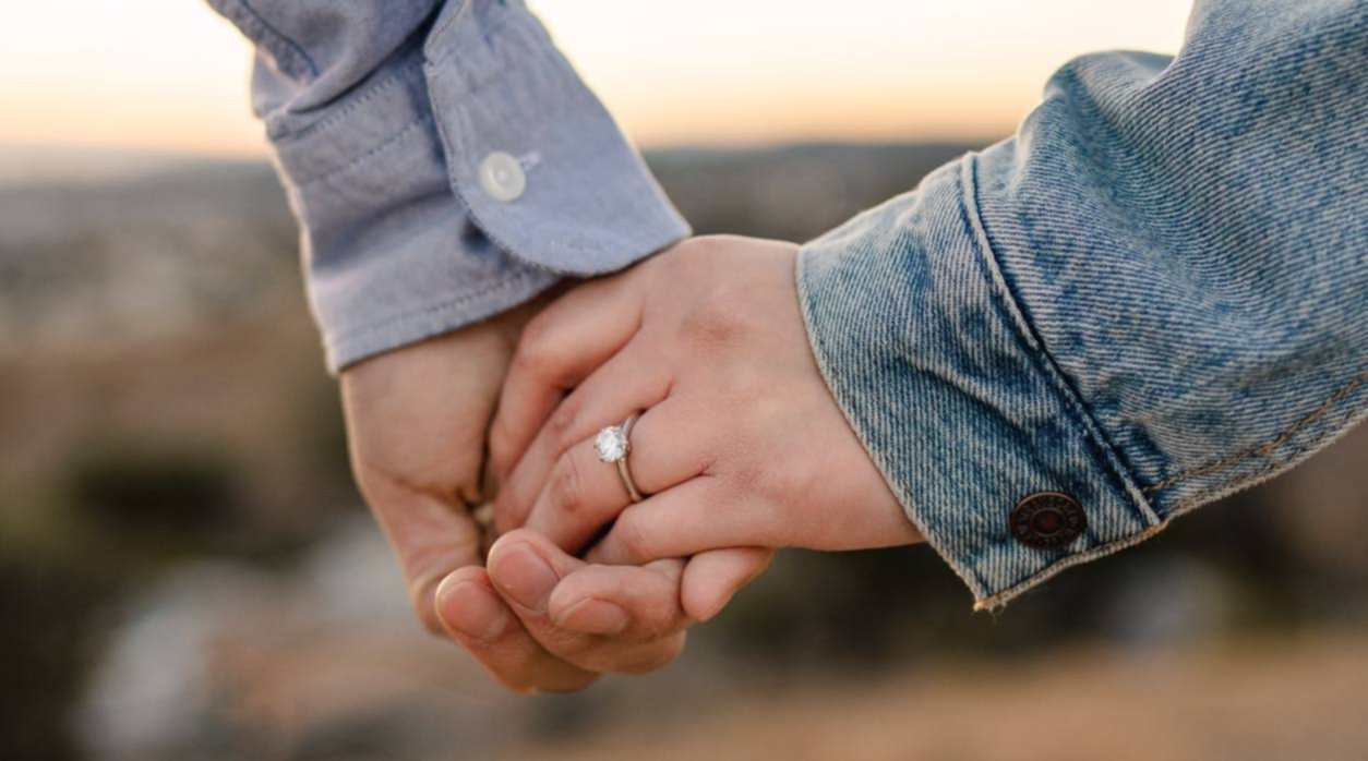 Holding hands. Woman wears a diamond ring.